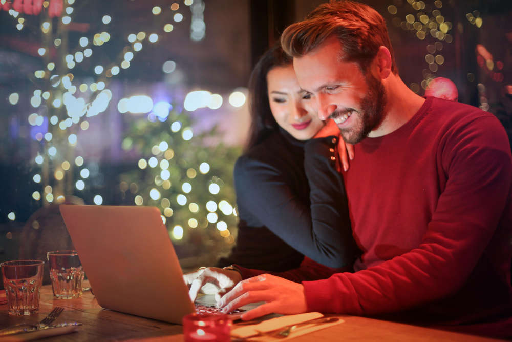 Happy couple sitting at a laptop shopping online.